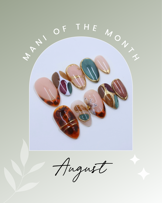 A manicure and nail art showcase graphic featuring multiple false nails with various designs including ombré, marbled patterns, and gold metallic lines. The nails are arranged inside a white arched frame on a soft sage green background with the text 'MANI OF THE MONTH' at the top and 'August' at the bottom.